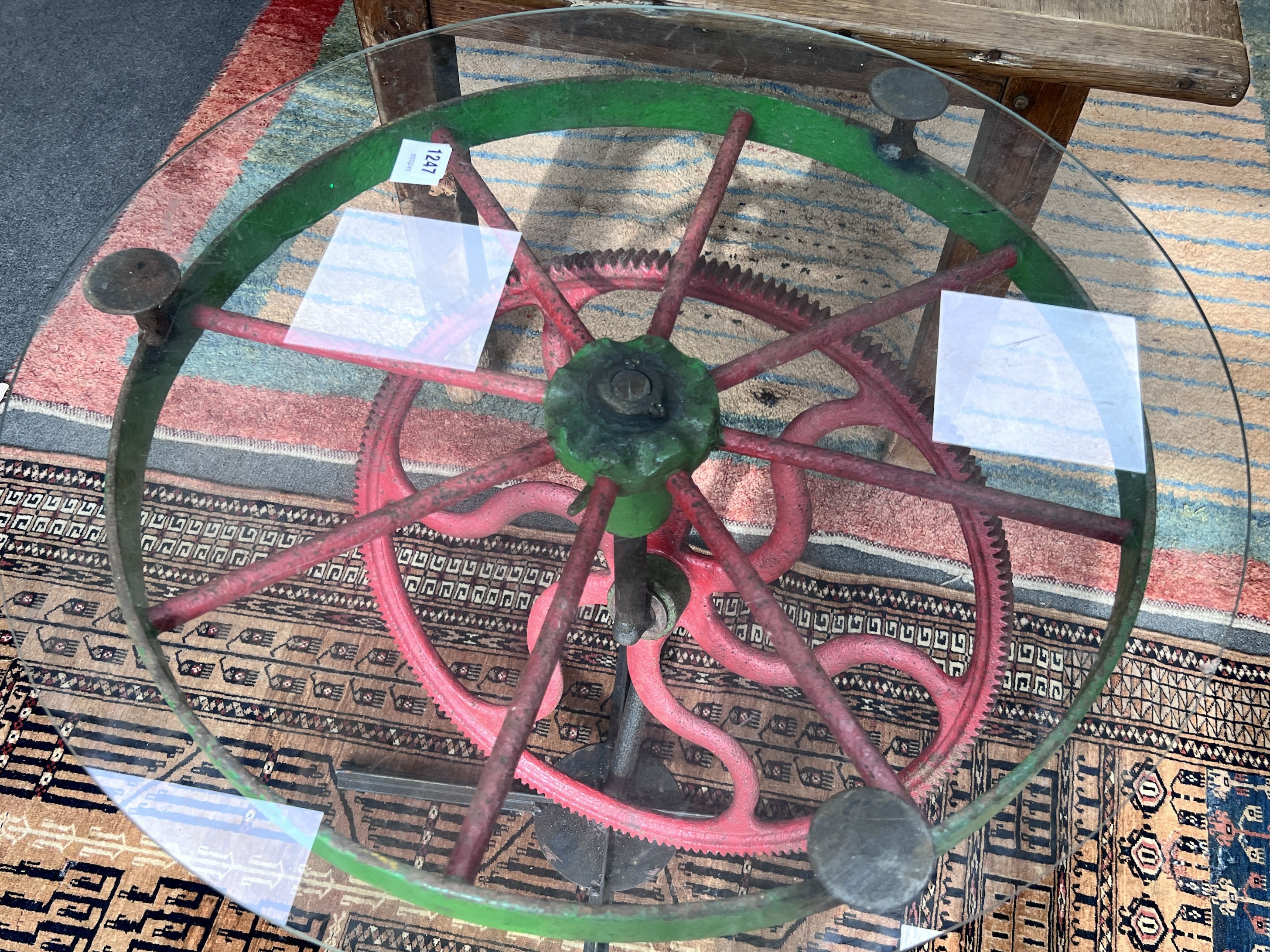 A wrought iron and glass occasional table constructed from cogs and wheels, diameter 70cm